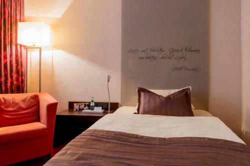 a hotel room with a bed and a chair at Atrium Hotel Mainz in Mainz