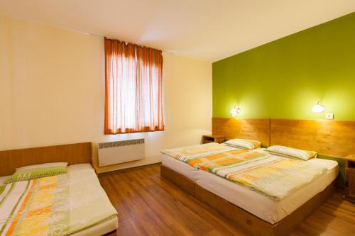 Habitación con 2 camas, paredes verdes y suelo de madera. en Sinia Vir Eco Residence en Medven