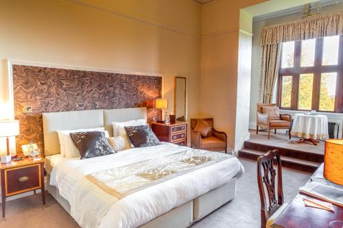 um quarto com uma cama grande e uma cadeira em Bagden Hall Hotel em Scissett