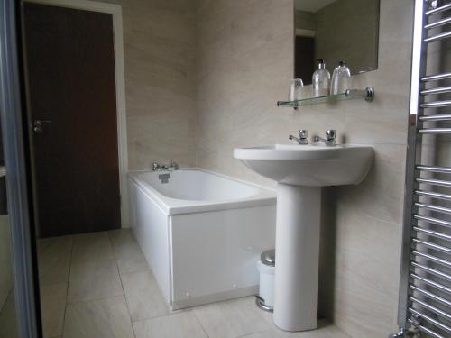 a bathroom with a sink and a bathtub at Greyhound Inn in Winterborne Kingston