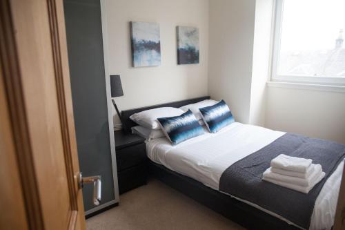una camera da letto con un letto con cuscini blu e una finestra di Apartment E ad Aberdeen
