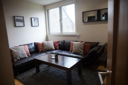 a living room with a black leather couch and a coffee table at Apartment E in Aberdeen