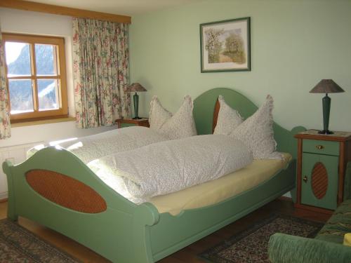 um quarto com uma cama verde e almofadas brancas em Ferienhaus Ebnerle em Heiligenblut