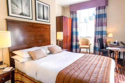 a hotel room with a large bed and a desk at White Swan Hotel in Alnwick