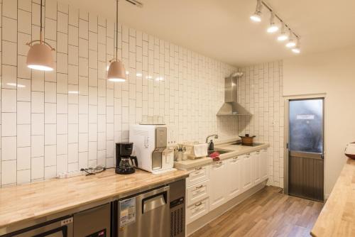 cocina con paredes de azulejos blancos y encimeras de madera en Hannahstay Women Only Guesthouse, en Jeju