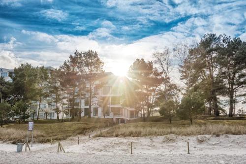 a house on a beach with the sun shining at Villa Vogue Gretas Beach Home in Binz