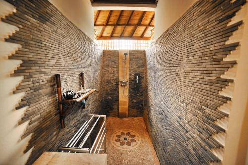 un couloir avec un mur en briques et une douche dans l'établissement Bali Dream House, à Amed