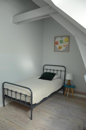 a bedroom with a metal bed in a attic at Gîte du Frêne in Fresnoy-le-Grand