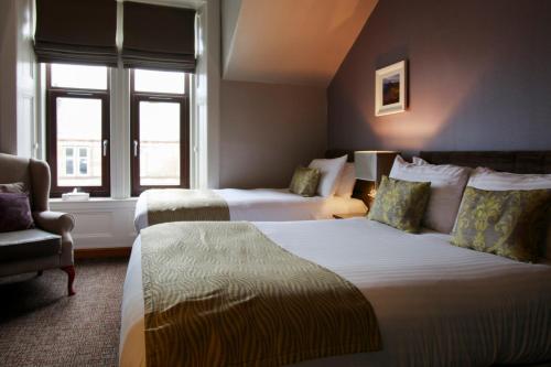 ein Hotelzimmer mit 2 Betten und einem Stuhl in der Unterkunft Angels Hotel in Uddingston