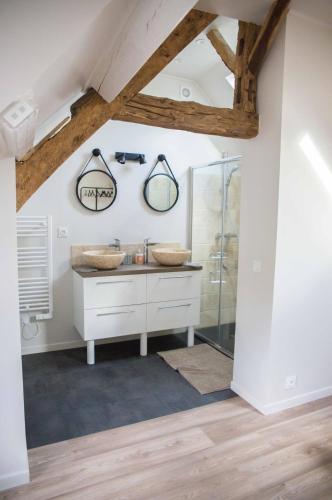 une salle de bain avec deux lavabos et une douche dans l'établissement Les maisons de Charlotte, à Glanville