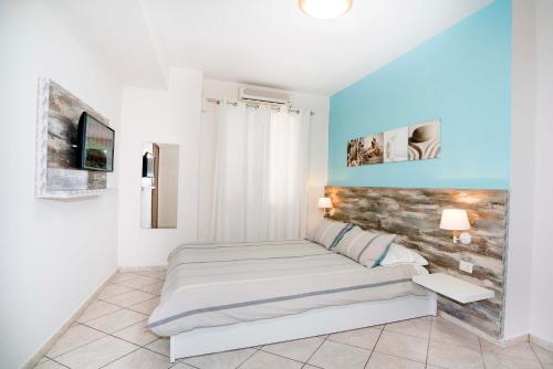 a white bedroom with a bed and a tv at Taormina Beach House in Mazzeo