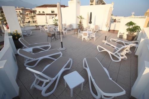 a patio area with chairs, tables and umbrellas at Hotel Puerta del Mar in Nerja