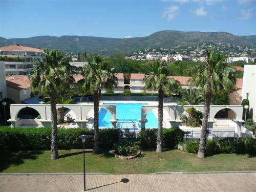 une vue d'un complexe avec piscine et palmiers dans l'établissement Résidence d'Azur 2 appartement 311, au Lavandou