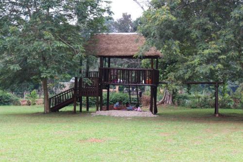 a small playground in a park with a tree at Bushbaby Lodge in Mukono
