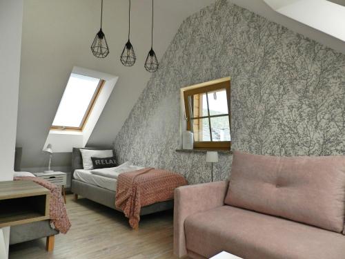 - une chambre avec un lit, un canapé et un miroir dans l'établissement Apartamenty EverySky - Osiedle Podgórze 1E, à Szklarska Poręba