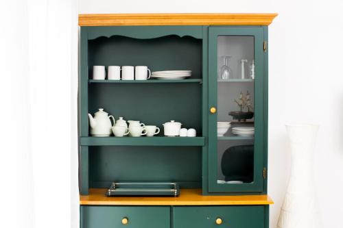 a green cabinet with plates and dishes in it at Atlantis Home in Antananarivo