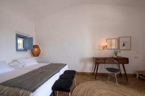 a bedroom with a bed and a desk and a chair at Herdade Do Touril in Zambujeira do Mar