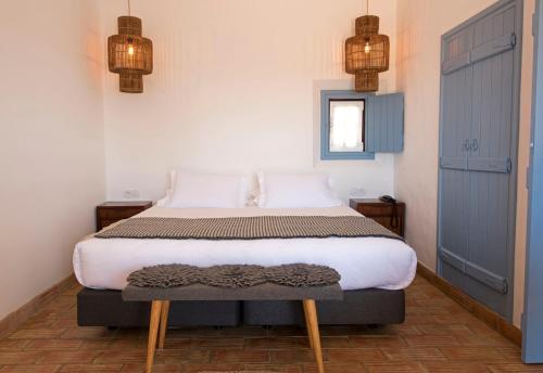 a bedroom with a bed and two lights on the wall at Herdade Do Touril in Zambujeira do Mar