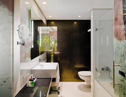 a bathroom with a sink and a toilet at H10 Berlin Ku'Damm in Berlin