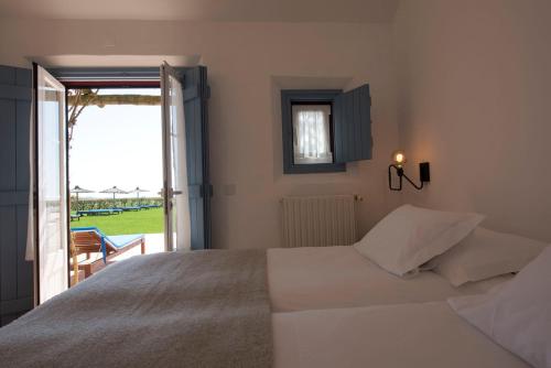 a bedroom with a bed and a door to a patio at Herdade Do Touril in Zambujeira do Mar