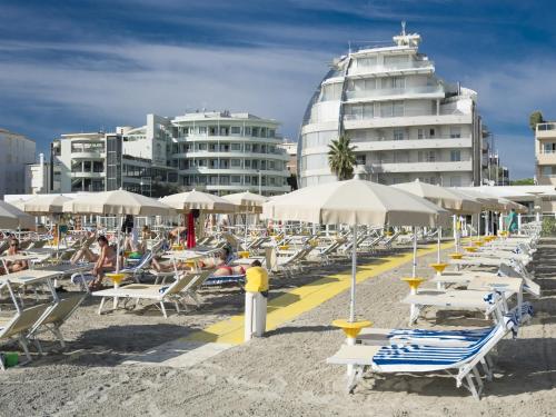 a group of chairs and umbrellas on a beach at Hotel Le Palme - Premier Resort in Milano Marittima