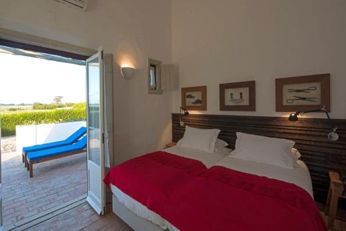 a bedroom with a bed and a sliding glass door at Herdade Do Touril in Zambujeira do Mar