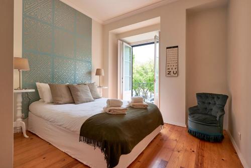 a bedroom with a bed and a chair and a window at Styling Apartment in Historic Center in Lisbon