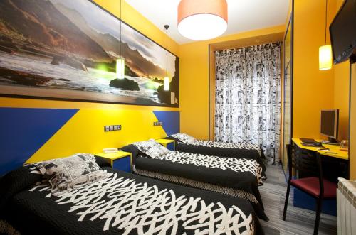 2 camas en una habitación con paredes amarillas en JC Rooms Santa Ana, en Madrid