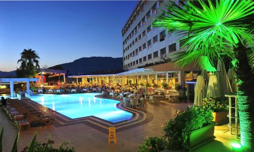 a large pool in a hotel with people sitting around it at Kırbıyık Resort Hotel - Alanya in Kargicak