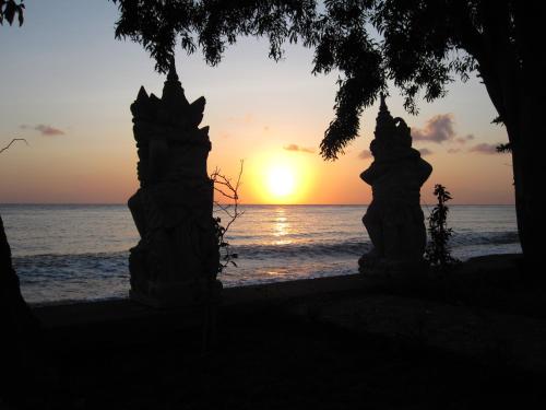 a sunset over the ocean with two statues at Bali Dream House in Amed