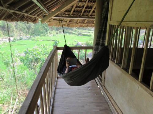a couple of people in a hammock on a porch at Dong Que Homestay-Tours-Motorbike, Car rental, Hiking in Ha Giang