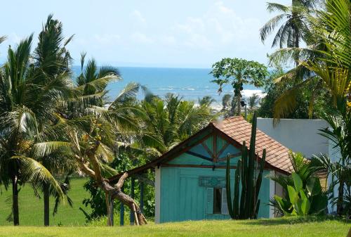 a blue house with palm trees in front of the ocean at Balian Prana in Selemadeg