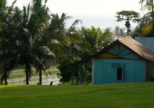 a small blue building with palm trees in a field at Balian Prana in Selemadeg