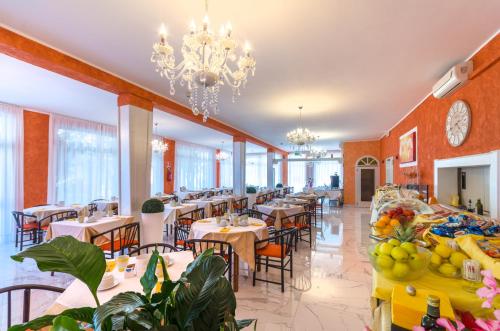 a restaurant with tables and chairs and a chandelier at Hotel Romantik & Depandance in Lignano Sabbiadoro