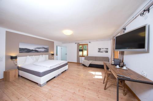 a bedroom with a bed and a couch and a television at Alpenhaus Kesselfall, Zell am See - Kaprun Sommercard included in Kaprun