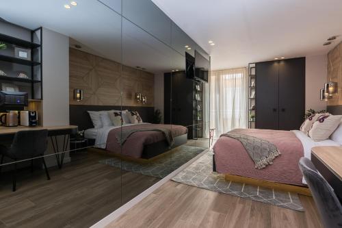 a bedroom with two beds and a desk and a television at Apartments & Rooms Mareta Exclusive in Zadar