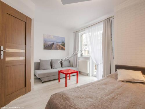 ヤスタルニャにあるDom Wczasowy MONIKAのベッドルーム1室(ベッド1台、赤いテーブル付)