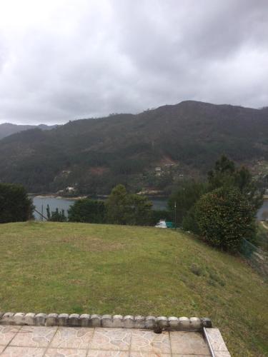 a grassy hill with a view of a river and mountains at Vale de Azereiros Apartamentos in Geres