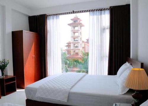 a bedroom with a bed and a window with a building at Sunflower Hotel in Ninh Binh