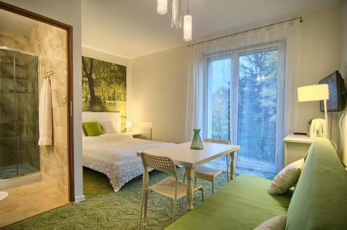 a bedroom with a bed and a table and a window at Pensjonat Magdalena in Szklarska Poręba