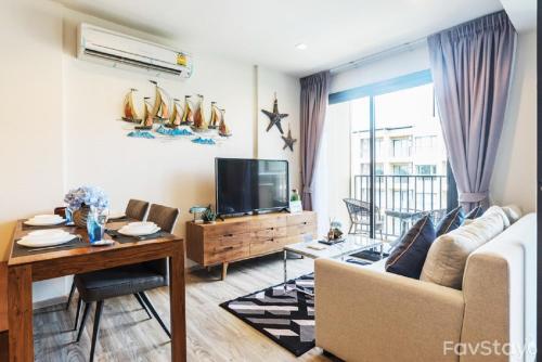a living room with a couch and a table and a tv at Rain Cha-am Huahin By Sake in Cha Am