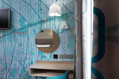 a bathroom with a mirror and a blue wall at Hotel Daumesnil-Vincennes in Vincennes