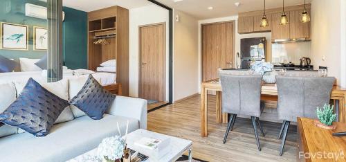 a living room with a couch and a dining room at Rain Cha-am Huahin By Sake in Cha Am