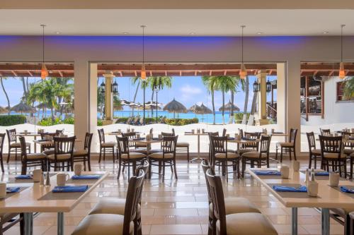 un restaurant avec des tables et des chaises et une vue sur l'océan dans l'établissement All Inclusive Holiday Inn Resort Aruba - Beach Resort & Casino by IHG, à Palm-Eagle Beach