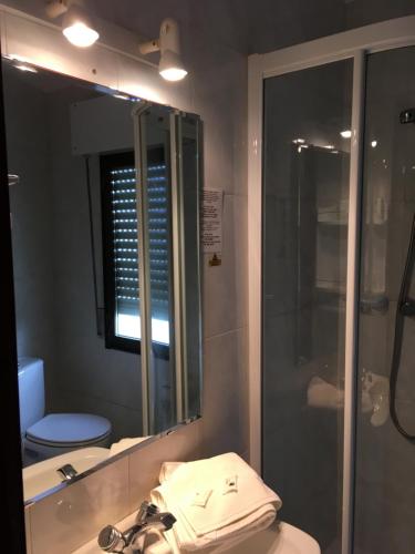 a bathroom with a shower and a sink and a mirror at Hotel Derli Sella in Ribadesella