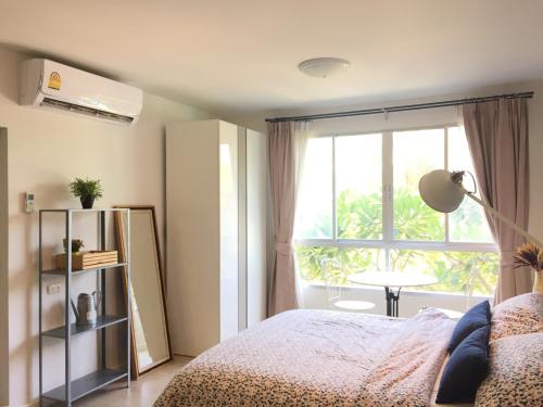 a bedroom with a bed and a window and a table at Baan Peang Ploen by Pattama in Hua Hin