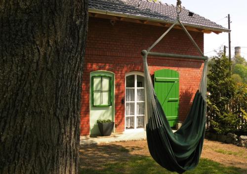 a hammock hanging from a tree in front of a house at Bahnhof Droyßig - Übernachten im Denkmal in Droyßig