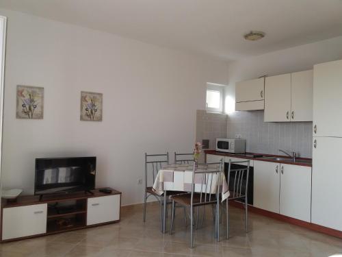 a kitchen with a table and a tv in a room at Guest House Lucija in Rab