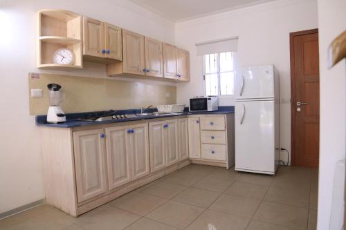 a kitchen with wooden cabinets and a white refrigerator at Residencial Las Estrellas in Boca Chica