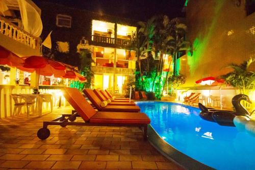 a swimming pool with lounge chairs and a hotel at Hotel Cabana Suiça in Guaratuba